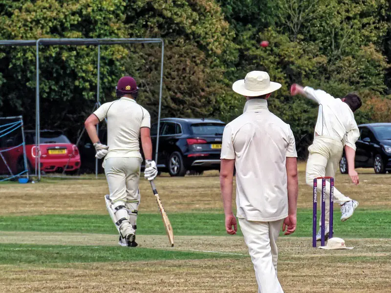 A bowler runs in past the non-striker, bat in hand, at a club ground in Essex